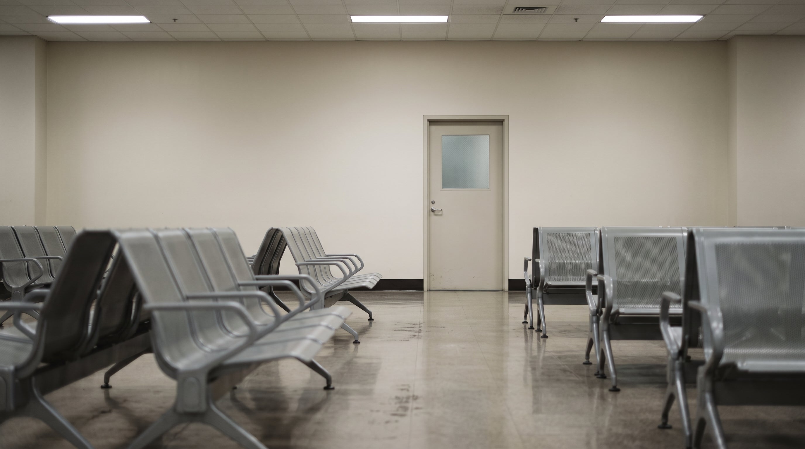 An empty airport arrivals hall, early morning, with a row of closed border control desks